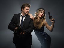 Ένα ζευγάρι των γκάγκστερ, ενός άνδρα και μιας γυναίκας με τα πυροβόλα όπλα στοκ εικόνες Ένα ζευγάρι των γκάγκστερ, ενός άνδρα και μιας γυναίκας με τα πυροβόλα όπλα στοκ εικόνες