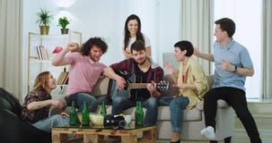 Ένα ζεύγος έχει ένα κόμμα στο σπίτι με τους φίλους τους στο καθιστικό αυτοί που τραγουδούν αστείο κιθάρων και να αισθανθεί έτσι απόθεμα βίντεο Ένα ζεύγος έχει ένα κόμμα στο σπίτι με τους φίλους τους στο καθιστικό αυτοί που τραγουδούν αστείο κιθάρων και να αισθανθεί έτσι απόθεμα βίντεο