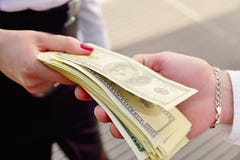 Ένα κορίτσι δίνει ένα άτομο στα χέρια των χρημάτων στο υπόβαθρο στοκ εικόνα Ένα κορίτσι δίνει ένα άτομο στα χέρια των χρημάτων στο υπόβαθρο στοκ εικόνα