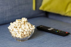 Ένα κύπελλο γυαλιού popcorn και του τηλεχειρισμού Να εξισώσει άνετο προσέχοντας έναν κινηματογράφο ή τη τηλεοπτική σειρά στο σπίτ στοκ εικόνα Ένα κύπελλο γυαλιού popcorn και του τηλεχειρισμού Να εξισώσει άνετο προσέχοντας έναν κινηματογράφο ή τη τηλεοπτική σειρά στο σπίτ στοκ εικόνα