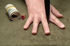 Ένα μαχαίρι μεταξύ των δάχτυλων ενός ανθρώπινου χεριού στο υπόβαθρο των δολαρίων και ενός χρυσού δαχτυλιδιού στοκ εικόνα με δικαίωμα ελεύθερης χρήσης Ένα μαχαίρι μεταξύ των δάχτυλων ενός ανθρώπινου χεριού στο υπόβαθρο των δολαρίων και ενός χρυσού δαχτυλιδιού στοκ εικόνα με δικαίωμα ελεύθερης χρήσης
