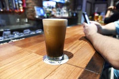 Ένα μεγάλο ψηλό ποτήρι της frothy εύγευστης μπύρας σε έναν φραγμό στοκ φωτογραφίες Ένα μεγάλο ψηλό ποτήρι της frothy εύγευστης μπύρας σε έναν φραγμό στοκ φωτογραφίες