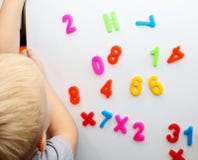 Ένα μικρό αγόρι μελετά τους μαγνητικούς αριθμούς στο ψυγείο Κατάρτιση Preschooler στοκ φωτογραφίες Ένα μικρό αγόρι μελετά τους μαγνητικούς αριθμούς στο ψυγείο Κατάρτιση Preschooler στοκ φωτογραφίες