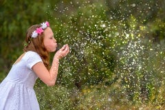 Ένα μικρό παιδί φυσά τα σπινθηρίσματα ή snowflakes σε ένα υπόβαθρο φύσης, έννοια διακοπών στοκ εικόνες Ένα μικρό παιδί φυσά τα σπινθηρίσματα ή snowflakes σε ένα υπόβαθρο φύσης, έννοια διακοπών στοκ εικόνες