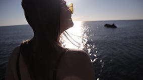 Ένα νέο κορίτσι κάθεται σε έναν βράχο και εξετάζει τη θάλασσα απόθεμα βίντεο Ένα νέο κορίτσι κάθεται σε έναν βράχο και εξετάζει τη θάλασσα απόθεμα βίντεο