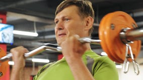 Ένα υπέρβαρο άτομο ανυψώνει ένα ez barbell στεμένος στη γυμναστική Άσκηση για τους δικέφαλους μυς E r απόθεμα βίντεο Ένα υπέρβαρο άτομο ανυψώνει ένα ez barbell στεμένος στη γυμναστική Άσκηση για τους δικέφαλους μυς E r απόθεμα βίντεο