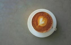 Ένα φλυτζάνι του καφέ cappuccino που διακοσμείται με το σχέδιο καρδιών στον καφετή αφρό γάλακτος στο λευκό στοκ εικόνα με δικαίωμα ελεύθερης χρήσης Ένα φλυτζάνι του καφέ cappuccino που διακοσμείται με το σχέδιο καρδιών στον καφετή αφρό γάλακτος στο λευκό στοκ εικόνα με δικαίωμα ελεύθερης χρήσης