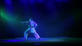 Ένας karate κύριος σε ένα άσπρο kimano με μια μαύρη ζώνη σε ένα μαύρο υπόβαθρο συμμετέχει karate απόθεμα βίντεο Ένας karate κύριος σε ένα άσπρο kimano με μια μαύρη ζώνη σε ένα μαύρο υπόβαθρο συμμετέχει karate απόθεμα βίντεο