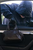Ένας άνδρας σε μια σκοτεινή κουκούλα κλέβει την τσάντα μιας γυναίκας μέσω ενός παραθύρου αυτοκινήτων στοκ φωτογραφία με δικαίωμα ελεύθερης χρήσης Ένας άνδρας σε μια σκοτεινή κουκούλα κλέβει την τσάντα μιας γυναίκας μέσω ενός παραθύρου αυτοκινήτων στοκ φωτογραφία με δικαίωμα ελεύθερης χρήσης