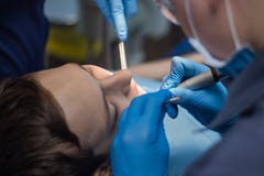 Ένας έφηβος μεταχειρίζεται τα δόντια στην οδοντιατρική Ο γιατρός του οδοντιάτρου και ο βοηθός διευθύνουν την υπομονετική αποδοχή στοκ φωτογραφίες με δικαίωμα ελεύθερης χρήσης Ένας έφηβος μεταχειρίζεται τα δόντια στην οδοντιατρική Ο γιατρός του οδοντιάτρου και ο βοηθός διευθύνουν την υπομονετική αποδοχή στοκ φωτογραφίες με δικαίωμα ελεύθερης χρήσης