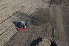 Ένας αγρότης σε ένα κόκκινο τρακτέρ με seeder σπέρνει το σιτάρι στο οργωμένο έδαφος σε έναν ιδιωτικό τομέα στην του χωριού περιοχ στοκ εικόνα Ένας αγρότης σε ένα κόκκινο τρακτέρ με seeder σπέρνει το σιτάρι στο οργωμένο έδαφος σε έναν ιδιωτικό τομέα στην του χωριού περιοχ στοκ εικόνα