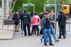 Ένας αστυνομικός ελέγχει τη μετάβαση των πολιτών μέσω του πλαισίου ανιχνευτών μετάλλων, πρίν εισάγει το εορταστικό γεγονός στοκ εικόνες Ένας αστυνομικός ελέγχει τη μετάβαση των πολιτών μέσω του πλαισίου ανιχνευτών μετάλλων, πρίν εισάγει το εορταστικό γεγονός στοκ εικόνες