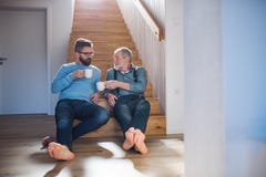 Ένας ενήλικος γιος hipster και μια ανώτερη συνεδρίαση πατέρων στα σκαλοπάτια στο εσωτερικό στο σπίτι, ομιλία στοκ φωτογραφίες με δικαίωμα ελεύθερης χρήσης Ένας ενήλικος γιος hipster και μια ανώτερη συνεδρίαση πατέρων στα σκαλοπάτια στο εσωτερικό στο σπίτι, ομιλία στοκ φωτογραφίες με δικαίωμα ελεύθερης χρήσης