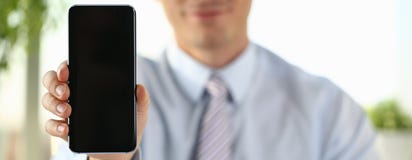 Ένας επιχειρηματίας κρατά ένα νέο smartphone στοκ εικόνα Ένας επιχειρηματίας κρατά ένα νέο smartphone στοκ εικόνα