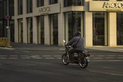 Ένας μοτοσυκλετιστής που διασχίζει μια ήρεμη οδό στο Ντίσελντορφ, Γερμανία στοκ εικόνα με δικαίωμα ελεύθερης χρήσης Ένας μοτοσυκλετιστής που διασχίζει μια ήρεμη οδό στο Ντίσελντορφ, Γερμανία στοκ εικόνα με δικαίωμα ελεύθερης χρήσης