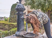Ένας νέος έφηβος με τη μακριά καφετιά τρίχα, πίνει σε μια πηγή μέσα σε Castillo Xativa στη Βαλένθια, Ισπανία στοκ φωτογραφία με δικαίωμα ελεύθερης χρήσης Ένας νέος έφηβος με τη μακριά καφετιά τρίχα, πίνει σε μια πηγή μέσα σε Castillo Xativa στη Βαλένθια, Ισπανία στοκ φωτογραφία με δικαίωμα ελεύθερης χρήσης