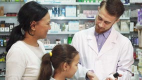Ένας νέος φαρμακοποιός μιλά για ένα από τα προϊόντα φαρμακείων στους πελάτες του στοκ εικόνες Ένας νέος φαρμακοποιός μιλά για ένα από τα προϊόντα φαρμακείων στους πελάτες του στοκ εικόνες