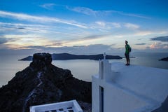 Ένας νεαρός άνδρας στέκεται στην άσπρη στέγη μιας εκκλησίας στο διάσημο ρομαντικό νησί Santorini στοκ φωτογραφίες Ένας νεαρός άνδρας στέκεται στην άσπρη στέγη μιας εκκλησίας στο διάσημο ρομαντικό νησί Santorini στοκ φωτογραφίες
