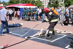 Ένας πυροσβέστης σε ένα αλεξίπυρο κοστούμι και ένα κράνος που κρατούν μια μάνικα πυρκαγιάς σε έναν αθλητικό ανταγωνισμό πυρκαγιάς στοκ φωτογραφία Ένας πυροσβέστης σε ένα αλεξίπυρο κοστούμι και ένα κράνος που κρατούν μια μάνικα πυρκαγιάς σε έναν αθλητικό ανταγωνισμό πυρκαγιάς στοκ φωτογραφία