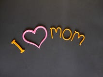 Αγαπώ τη μητέρα μου η επιγραφή του κίτρινου plasticine με μια ρόδινη καρδιά στοκ εικόνες Αγαπώ τη μητέρα μου η επιγραφή του κίτρινου plasticine με μια ρόδινη καρδιά στοκ εικόνες