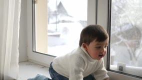 Αγοράκι στην άσπρη πλεκτή συνεδρίαση πουλόβερ από το παράθυρο το χειμώνα φιλμ μικρού μήκους Αγοράκι στην άσπρη πλεκτή συνεδρίαση πουλόβερ από το παράθυρο το χειμώνα φιλμ μικρού μήκους