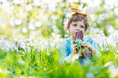Αγόρι παιδάκι που τρώει το λαγουδάκι Πάσχας σοκολάτας υπαίθρια Στοκ Φωτογραφία Αγόρι παιδάκι που τρώει το λαγουδάκι Πάσχας σοκολάτας υπαίθρια Στοκ Φωτογραφία