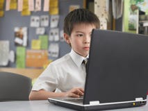 Αγόρι που χρησιμοποιεί το lap-top στην τάξη στοκ εικόνα με δικαίωμα ελεύθερης χρήσης Αγόρι που χρησιμοποιεί το lap-top στην τάξη στοκ εικόνα με δικαίωμα ελεύθερης χρήσης