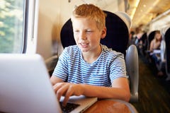 Αγόρι που χρησιμοποιεί το lap-top στο ταξίδι τραίνων στοκ φωτογραφίες με δικαίωμα ελεύθερης χρήσης Αγόρι που χρησιμοποιεί το lap-top στο ταξίδι τραίνων στοκ φωτογραφίες με δικαίωμα ελεύθερης χρήσης