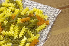 Ακατέργαστα χρωματισμένα ζυμαρικά fusilli burlap με την κινηματογράφηση σε πρώτο πλάνο στοκ εικόνα Ακατέργαστα χρωματισμένα ζυμαρικά fusilli burlap με την κινηματογράφηση σε πρώτο πλάνο στοκ εικόνα