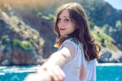 Ακολουθήστε με, το ελκυστικό κορίτσι brunette που κρατούν τους μολύβδους χεριών στα βουνά και την μπλε θάλασσα στοκ εικόνα Ακολουθήστε με, το ελκυστικό κορίτσι brunette που κρατούν τους μολύβδους χεριών στα βουνά και την μπλε θάλασσα στοκ εικόνα