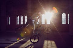 Ακροβατική επίδειξη BMX και οδήγηση άλματος σε μια αίθουσα με το φως του ήλιου στοκ εικόνες Ακροβατική επίδειξη BMX και οδήγηση άλματος σε μια αίθουσα με το φως του ήλιου στοκ εικόνες