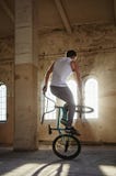 Ακροβατική επίδειξη BMX και οδήγηση άλματος σε μια αίθουσα με το φως του ήλιου στοκ εικόνες με δικαίωμα ελεύθερης χρήσης Ακροβατική επίδειξη BMX και οδήγηση άλματος σε μια αίθουσα με το φως του ήλιου στοκ εικόνες με δικαίωμα ελεύθερης χρήσης