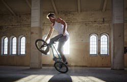 Ακροβατική επίδειξη BMX και οδήγηση άλματος σε μια αίθουσα με το φως του ήλιου στοκ εικόνες με δικαίωμα ελεύθερης χρήσης Ακροβατική επίδειξη BMX και οδήγηση άλματος σε μια αίθουσα με το φως του ήλιου στοκ εικόνες με δικαίωμα ελεύθερης χρήσης