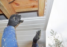 Ανάδοχος που εγκαθιστά soffit τους πίνακες στην κατασκευή υλικού κατασκευής σκεπής σπιτιών στοκ εικόνες Ανάδοχος που εγκαθιστά soffit τους πίνακες στην κατασκευή υλικού κατασκευής σκεπής σπιτιών στοκ εικόνες