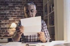 Ανησυχημένο άτομο που ελέγχει τους εσωτερικούς λογαριασμούς του στο σπίτι στοκ φωτογραφίες με δικαίωμα ελεύθερης χρήσης Ανησυχημένο άτομο που ελέγχει τους εσωτερικούς λογαριασμούς του στο σπίτι στοκ φωτογραφίες με δικαίωμα ελεύθερης χρήσης