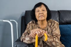 Ανώτερη γυναίκα με τον κάλαμο που στηρίζεται και που κάθεται στον καναπέ στοκ φωτογραφία με δικαίωμα ελεύθερης χρήσης Ανώτερη γυναίκα με τον κάλαμο που στηρίζεται και που κάθεται στον καναπέ στοκ φωτογραφία με δικαίωμα ελεύθερης χρήσης
