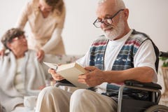 Ανώτερο άτομο στην αναπηρική καρέκλα που διαβάζει ένα βιβλίο στοκ φωτογραφία με δικαίωμα ελεύθερης χρήσης Ανώτερο άτομο στην αναπηρική καρέκλα που διαβάζει ένα βιβλίο στοκ φωτογραφία με δικαίωμα ελεύθερης χρήσης