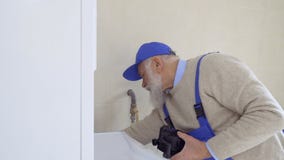 Ανώτερο γκρίζος-μαλλιαρό άτομο που φορά το λέβητα επισκευών φορμών φιλμ μικρού μήκους Ανώτερο γκρίζος-μαλλιαρό άτομο που φορά το λέβητα επισκευών φορμών φιλμ μικρού μήκους