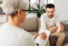 Ανώτερος ψυχολόγος γυναικών και λυπημένος ασθενής ανδρών στοκ εικόνες με δικαίωμα ελεύθερης χρήσης Ανώτερος ψυχολόγος γυναικών και λυπημένος ασθενής ανδρών στοκ εικόνες με δικαίωμα ελεύθερης χρήσης