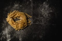 Απομονωμένα ακατέργαστα ζυμαρικά σε ένα μαύρο υπόβαθρο με μια θέση για το κείμενο Παραδοσιακά ιταλικά ζυμαρικά, νουντλς, tagliate στοκ εικόνες με δικαίωμα ελεύθερης χρήσης Απομονωμένα ακατέργαστα ζυμαρικά σε ένα μαύρο υπόβαθρο με μια θέση για το κείμενο Παραδοσιακά ιταλικά ζυμαρικά, νουντλς, tagliate στοκ εικόνες με δικαίωμα ελεύθερης χρήσης