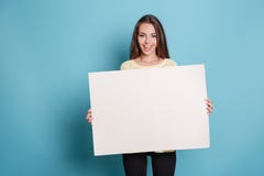 Αρκετά νέα γυναίκα που κρατά τον κενό κενό πίνακα πέρα από το μπλε υπόβαθρο Στοκ Εικόνες Αρκετά νέα γυναίκα που κρατά τον κενό κενό πίνακα πέρα από το μπλε υπόβαθρο Στοκ Εικόνες