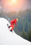 Αρσενικό snowboarder ελεύθερο σε ένα κόκκινο κοστούμι που οδηγά από την κορυφή του χιονώδους λόφου με το σνόουμπορντ στοκ φωτογραφία με δικαίωμα ελεύθερης χρήσης Αρσενικό snowboarder ελεύθερο σε ένα κόκκινο κοστούμι που οδηγά από την κορυφή του χιονώδους λόφου με το σνόουμπορντ στοκ φωτογραφία με δικαίωμα ελεύθερης χρήσης
