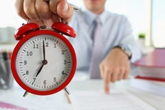 Αρσενικό χέρι στο ξυπνητήρι ένα κόκκινο στοκ φωτογραφία με δικαίωμα ελεύθερης χρήσης Αρσενικό χέρι στο ξυπνητήρι ένα κόκκινο στοκ φωτογραφία με δικαίωμα ελεύθερης χρήσης