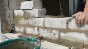Αρσενικός οικοδόμος που βάζει το άσπρο τούβλο στο τσιμέντο και που στέκεται τον τοίχο Τα χέρια του ατόμου που βάζει τα τούβλα οικ φιλμ μικρού μήκους Αρσενικός οικοδόμος που βάζει το άσπρο τούβλο στο τσιμέντο και που στέκεται τον τοίχο Τα χέρια του ατόμου που βάζει τα τούβλα οικ φιλμ μικρού μήκους
