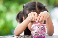 Ασιάτης λίγο κορίτσι παιδιών που βάζει τα χρήματα στη piggy τράπεζα στοκ φωτογραφίες Ασιάτης λίγο κορίτσι παιδιών που βάζει τα χρήματα στη piggy τράπεζα στοκ φωτογραφίες