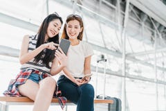 Ασιατικά κορίτσια που χρησιμοποιούν το smartphone που ελέγχει την πτήση ή τη σε απευθείας σύνδεση είσοδο στον αερολιμένα μαζί, με στοκ εικόνες Ασιατικά κορίτσια που χρησιμοποιούν το smartphone που ελέγχει την πτήση ή τη σε απευθείας σύνδεση είσοδο στον αερολιμένα μαζί, με στοκ εικόνες