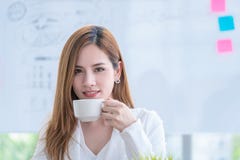 Ασιατική επιχειρησιακή γυναίκα που ελέγχει την έκθεση πίνοντας τον καφέ στοκ φωτογραφία με δικαίωμα ελεύθερης χρήσης Ασιατική επιχειρησιακή γυναίκα που ελέγχει την έκθεση πίνοντας τον καφέ στοκ φωτογραφία με δικαίωμα ελεύθερης χρήσης