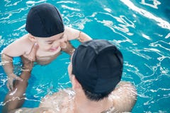 Ασιατική πισίνα μαθημάτων πατέρων και μωρών στο νερό στοκ φωτογραφία με δικαίωμα ελεύθερης χρήσης Ασιατική πισίνα μαθημάτων πατέρων και μωρών στο νερό στοκ φωτογραφία με δικαίωμα ελεύθερης χρήσης