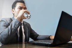 Ασιατικός επιχειρηματίας στο γκρίζο πόσιμο νερό κοστουμιών Χρησιμοποίηση και τουαλέτα ατόμων στοκ φωτογραφία με δικαίωμα ελεύθερης χρήσης Ασιατικός επιχειρηματίας στο γκρίζο πόσιμο νερό κοστουμιών Χρησιμοποίηση και τουαλέτα ατόμων στοκ φωτογραφία με δικαίωμα ελεύθερης χρήσης
