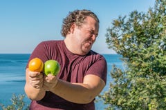 Αστείο παχύ άτομο στον ωκεανό που τρώει τα φρούτα Διακοπές, απώλεια βάρους και υγιής κατανάλωση στοκ φωτογραφία Αστείο παχύ άτομο στον ωκεανό που τρώει τα φρούτα Διακοπές, απώλεια βάρους και υγιής κατανάλωση στοκ φωτογραφία